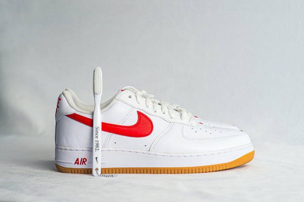 Detailed view of a white sneaker with red swoosh and gum sole.